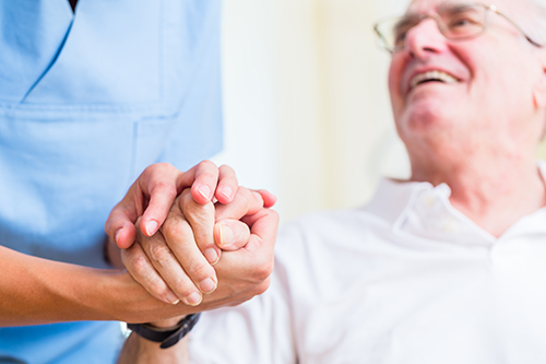 Nurse holding hand of a senior man in a rest home