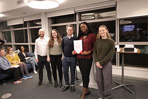 Two men and three women in a row, one holding a certificate