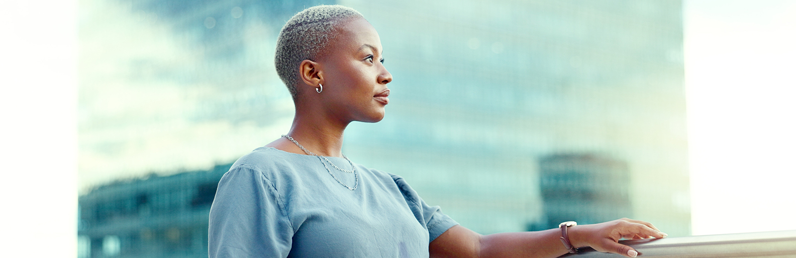 Woman on balcony in the city looking hopefully into the distance