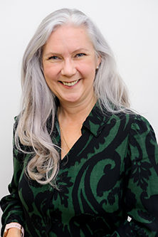 Photo of Maggie with long white hair, wearing green top against a while background