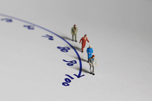 Aged miniature figures moving along a timeline