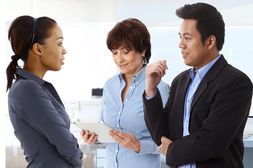 Two women and man stand talking in the office