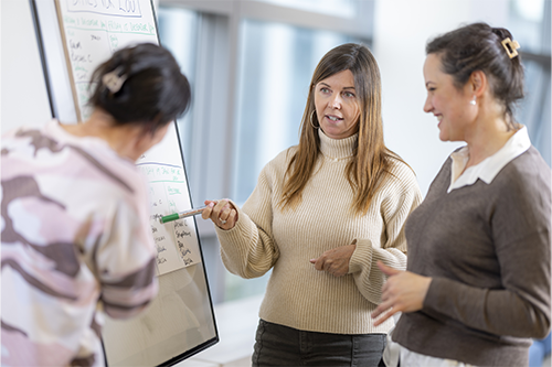 3 ladies next to a white board