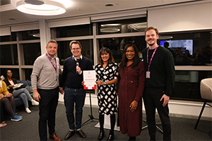 five people in a line with one holding a certificate