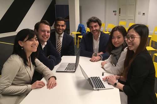 students and clients sitting around a table smiling