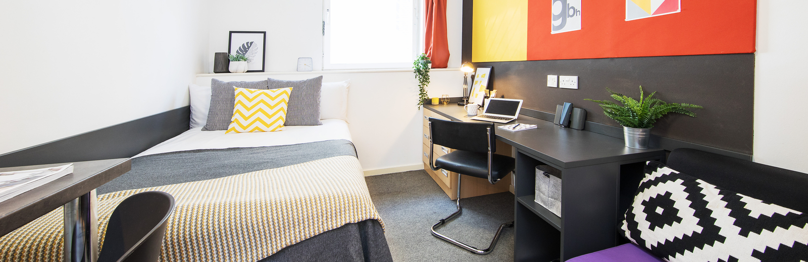 Single bedroom with bright colour scheme. Showing bed, work desk and chair, table, small sofa and rear window.