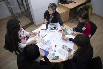 Group of women working together at a table with a variety of magazines