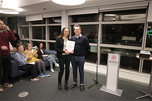 A woman stands with a certificate beside a man
