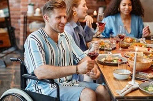 Man in a wheelchair eating with his family.