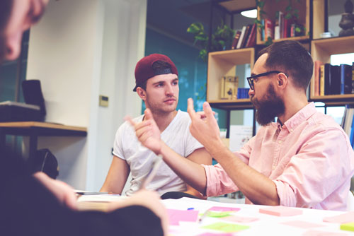 Two young entrepreneurs discuss business at a table.