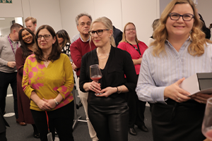 A woman stands with a small giftbox and two other women are in the background