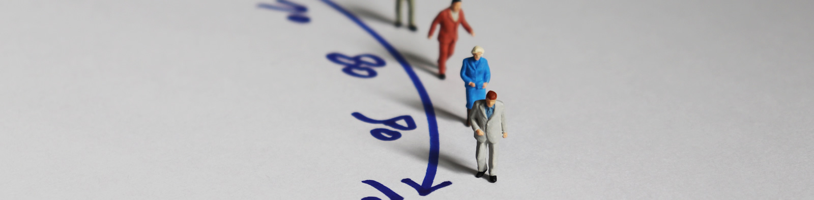 Aged miniature figures moving along a timeline