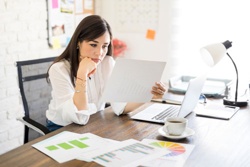 woman working from home with laptop and paperwork