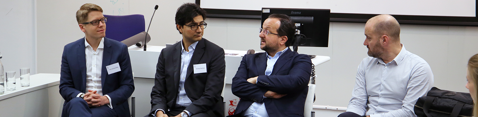 four men sit alongside eachother in thought
