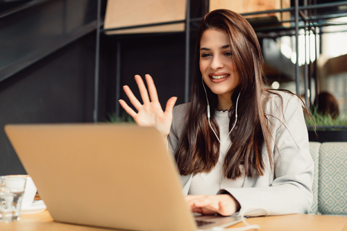 woman smiling into a video conference call on laptop