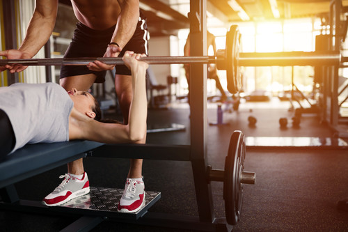 A woman benchpresses in the gym
