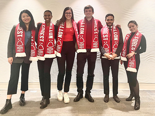 Group of young women and men posing in a line wearing red and white football scarves.