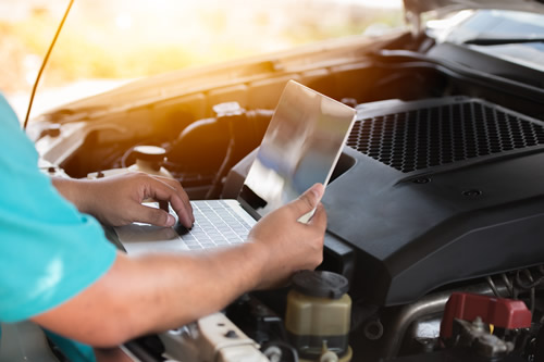 Mechanic checking the software system of a car with laptop