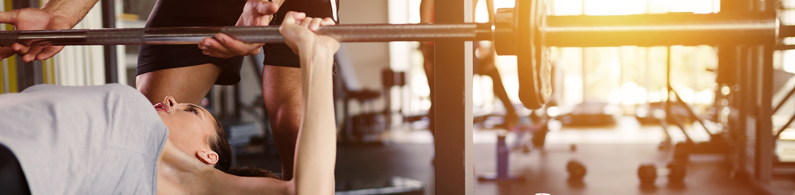 A woman benchpresses in the gym