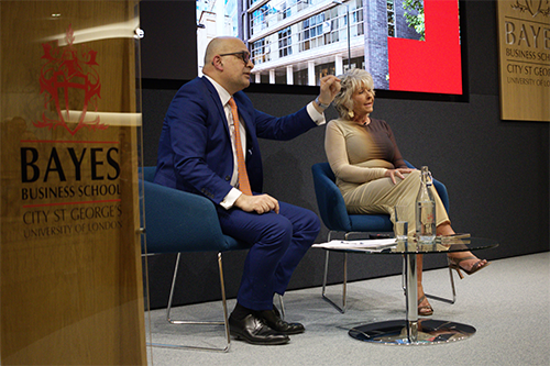 An Asian man and a white woman sit looking out at the audience during the question and answer session