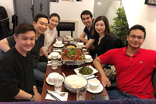 Oliver and other students around a table filled with food in an Asian restaurant.