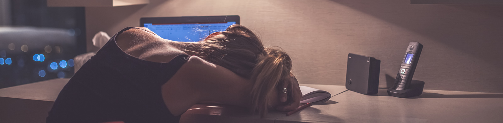 Female worker slumped, exhausted, at her desk