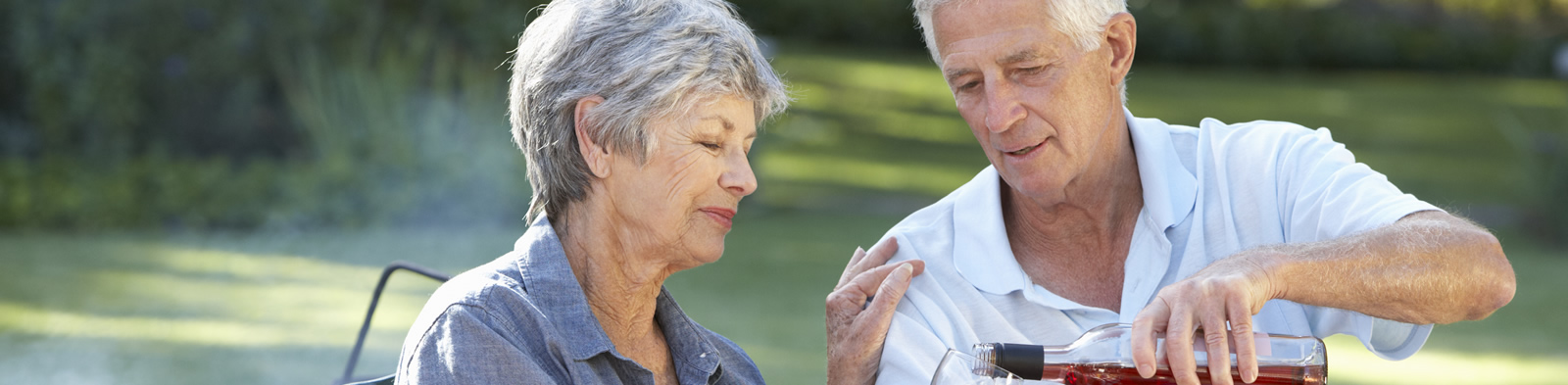 Senior couple enjoying a barbecue in the garden with wine