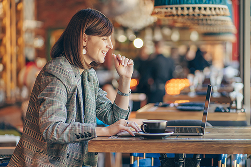 Woman working on a laptop with a cup of coffee in a cafe