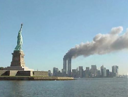 The Statue of Liberty is in the foreground with smoke billowing from the Twin Towers