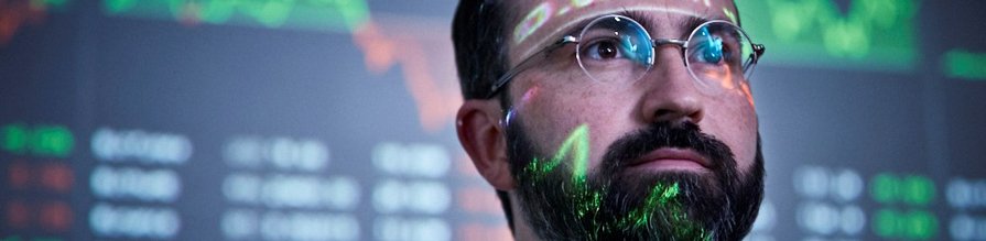 Man with stock market figures reflecting on his face