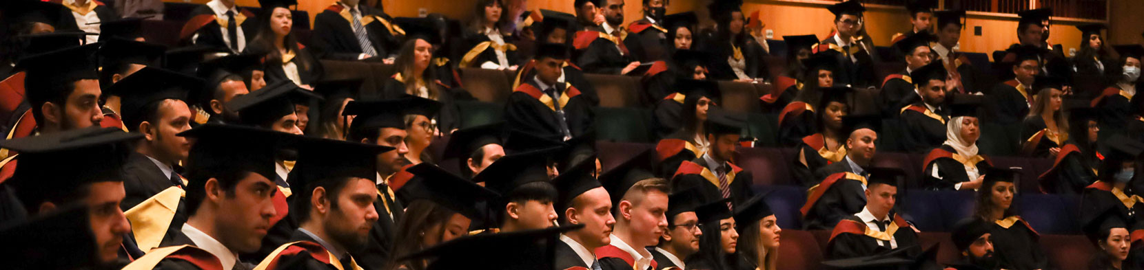 Three male Bayes graduates doff their caps 